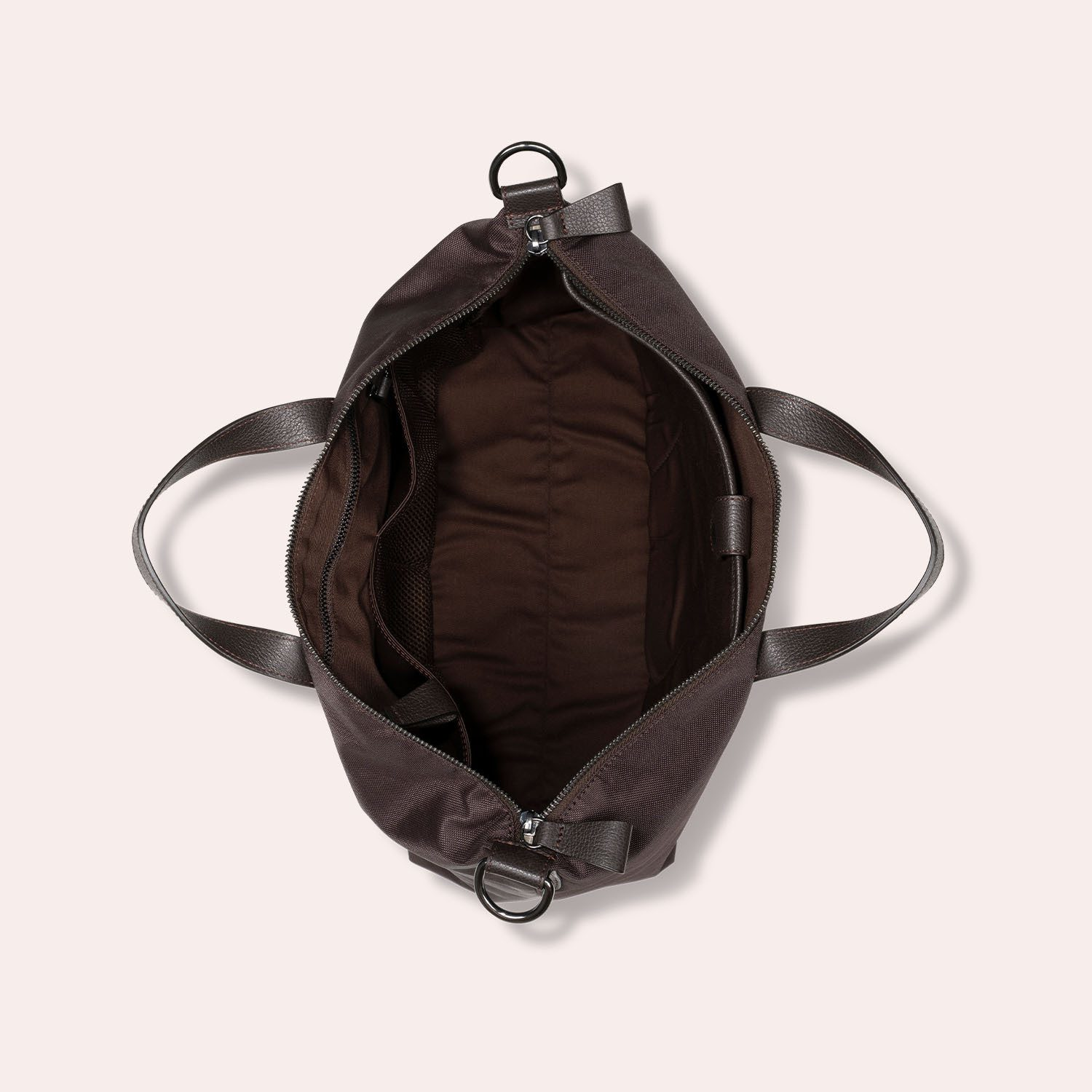 Draufsicht auf eine offene dunkelbraune Tragetasche mit zwei Henkeln und einem geräumigen, leeren Innenraum, der eine Reißverschlusstasche und ein dunkles Stofffutter zeigt, vor einem hellen Hintergrund.