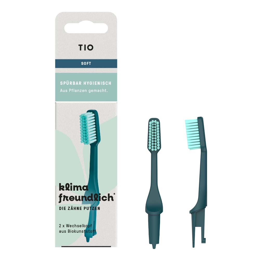 Die Verpackung für die weichen Zahnbürstenköpfe von TIO mit zwei Ersatzköpfen ist neben der Schachtel abgebildet. Die Schachtel hebt hervor, dass das Produkt pflanzlich und klimafreundlich ist, mit Text auf Deutsch.