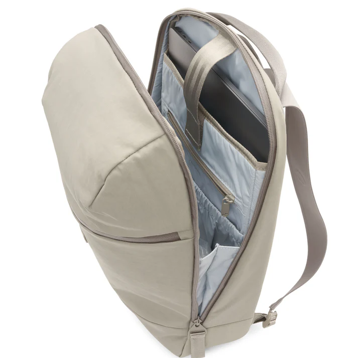 Ein beiger Rucksack mit geöffnetem Deckel, der organisierte Innentaschen mit Laptop, Tablet und Reißverschlussfach sowie hellgraues Futter und verstellbare Schulterriemen offenbart.