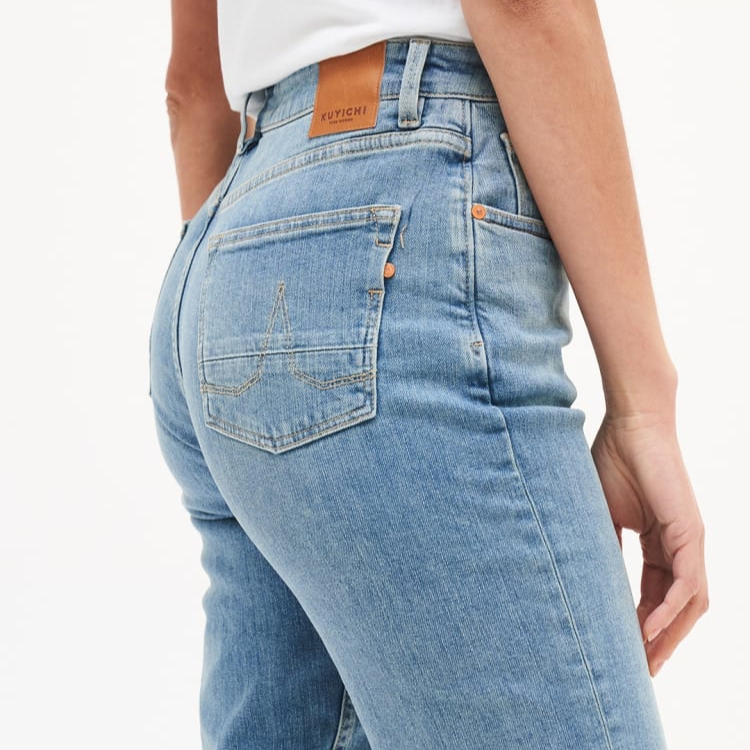 Person trägt eine blaue Jeans mit einer braunen Etikett auf der Rückseite.