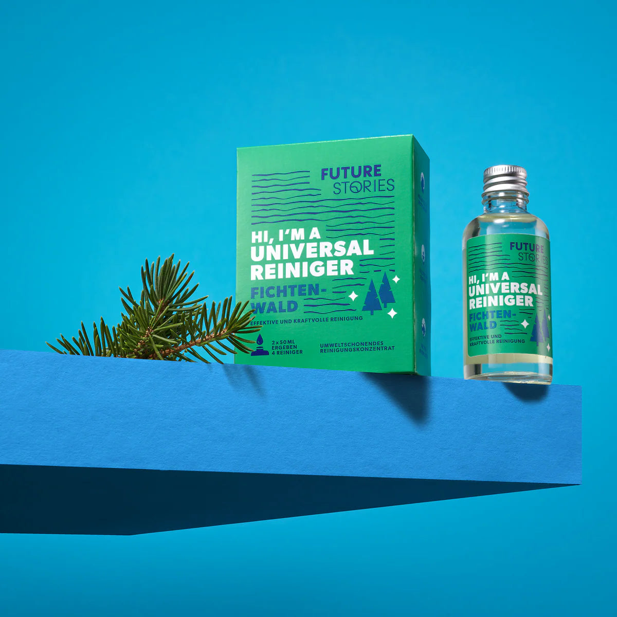 Eine grüne Schachtel und eine durchsichtige Flasche mit der Aufschrift "Universal Reiniger" stehen auf einer blauen Fläche neben einem Tannenzweig mit blauem Hintergrund. Die Verpackung zeigt eine Baumgrafik und einen Text in deutscher Sprache.