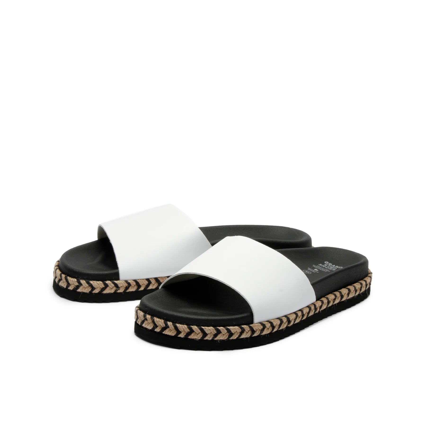 Weiße Sandalen mit breiten Riemen und schwarzer Sohle, die mit geflochtenem Bast verziert ist.