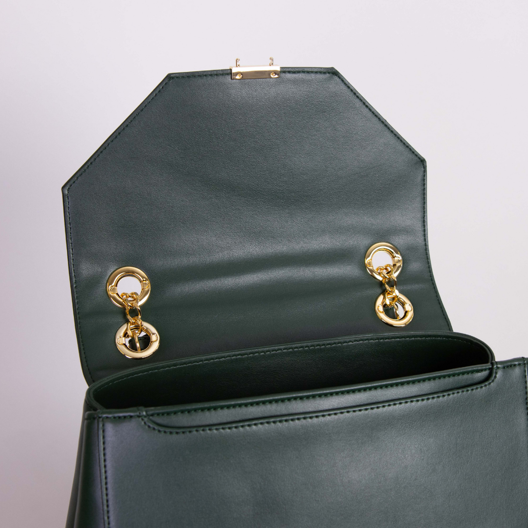 Geöffnete, dunkelgrüne Ledertasche mit goldenen Akzenten und einem achteckigen Deckel.