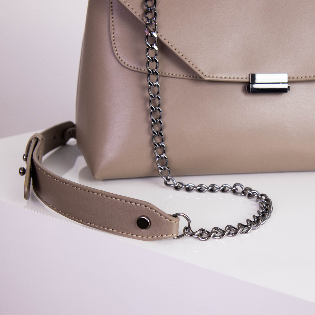 Beige Handtasche mit Kettenriemen auf weißem Hintergrund.