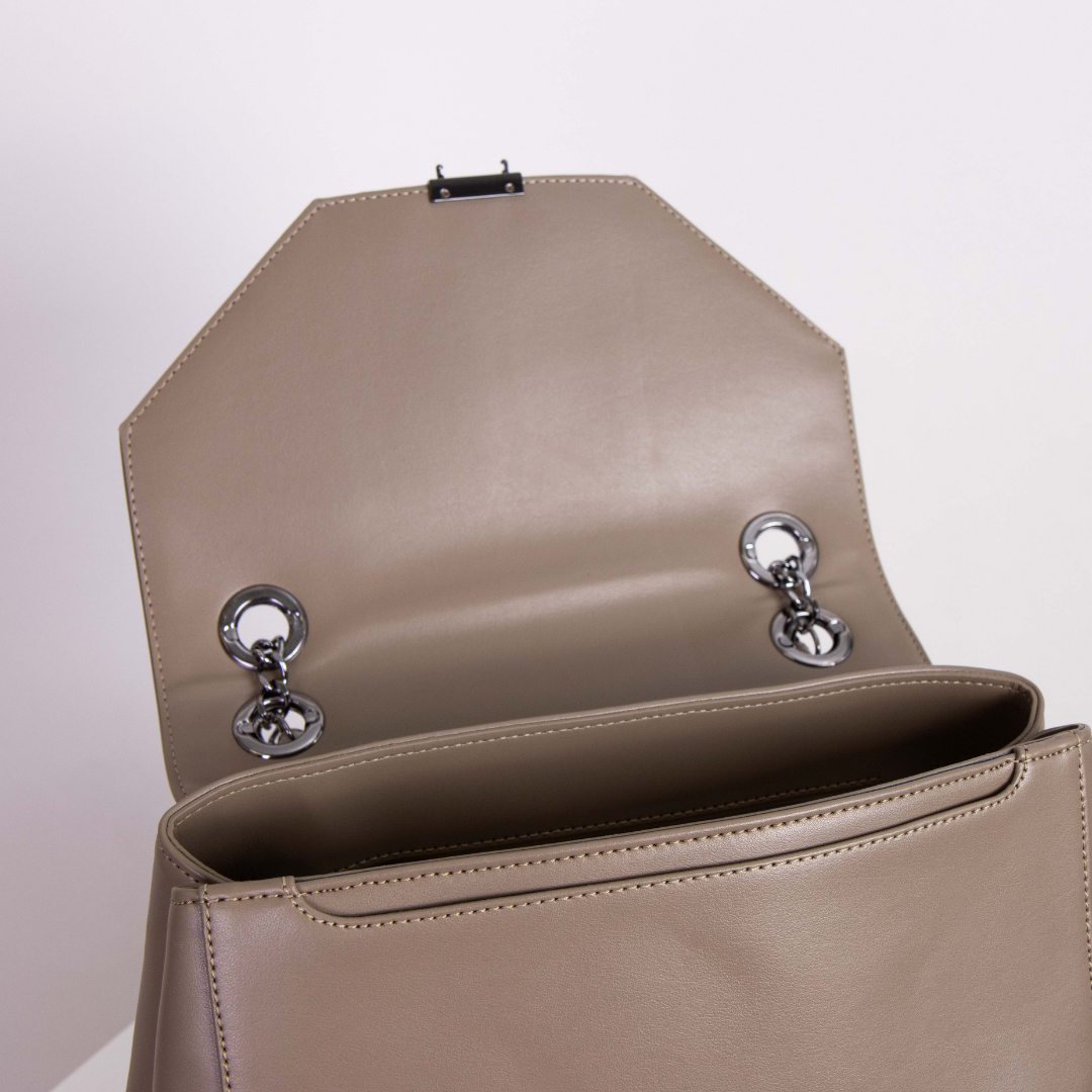 Beige Ledertasche mit offenem Überschlag und silbernen Kettenringen im Inneren, auf weißem Hintergrund.