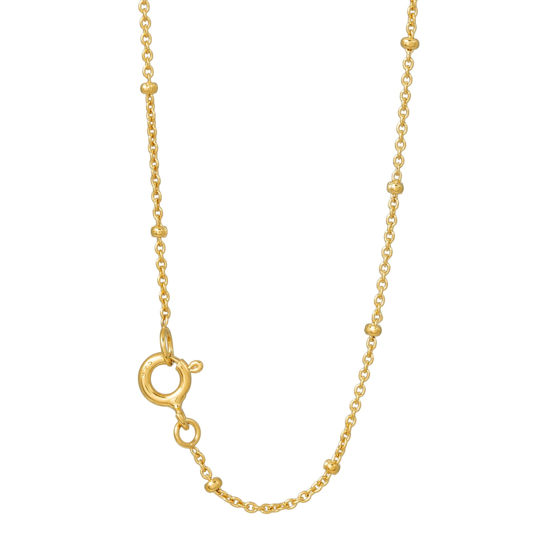 Nahaufnahme einer zarten Goldkette mit kleinen, gleichmäßig verteilten Perlenakzenten und einem runden Federringverschluss.