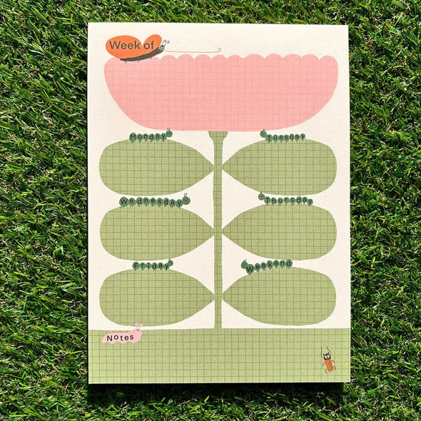 Kalenderblatt in Blumenform auf grünem Hintergrund, mit Wochentagen und Notizfeld.