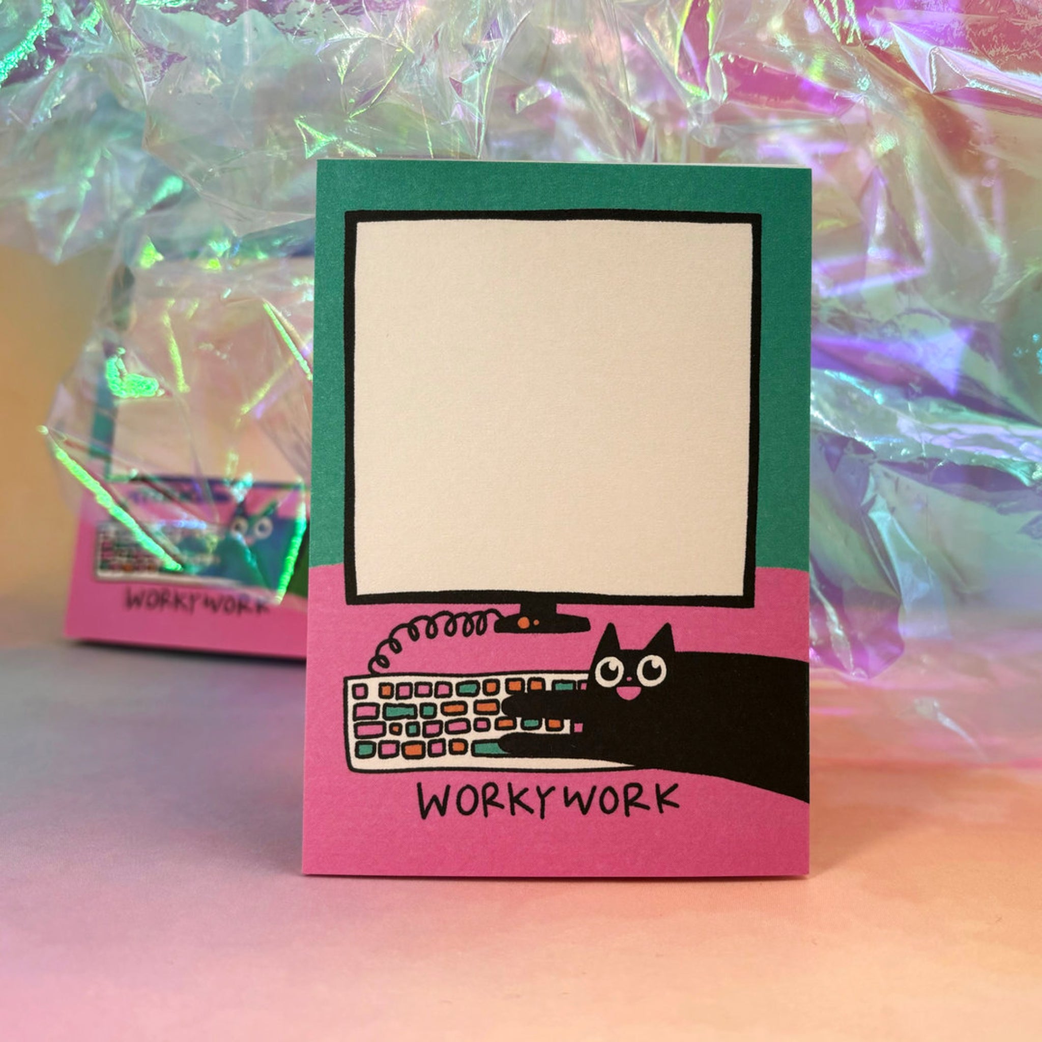 Eine bunte Notizkarte mit der Aufschrift „WORKY WORK“, zeigt eine Katze vor einem leeren Monitor und einer Tastatur.