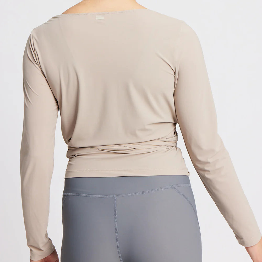 Person in beige long-sleeve top and gray leggings, viewed from the back.