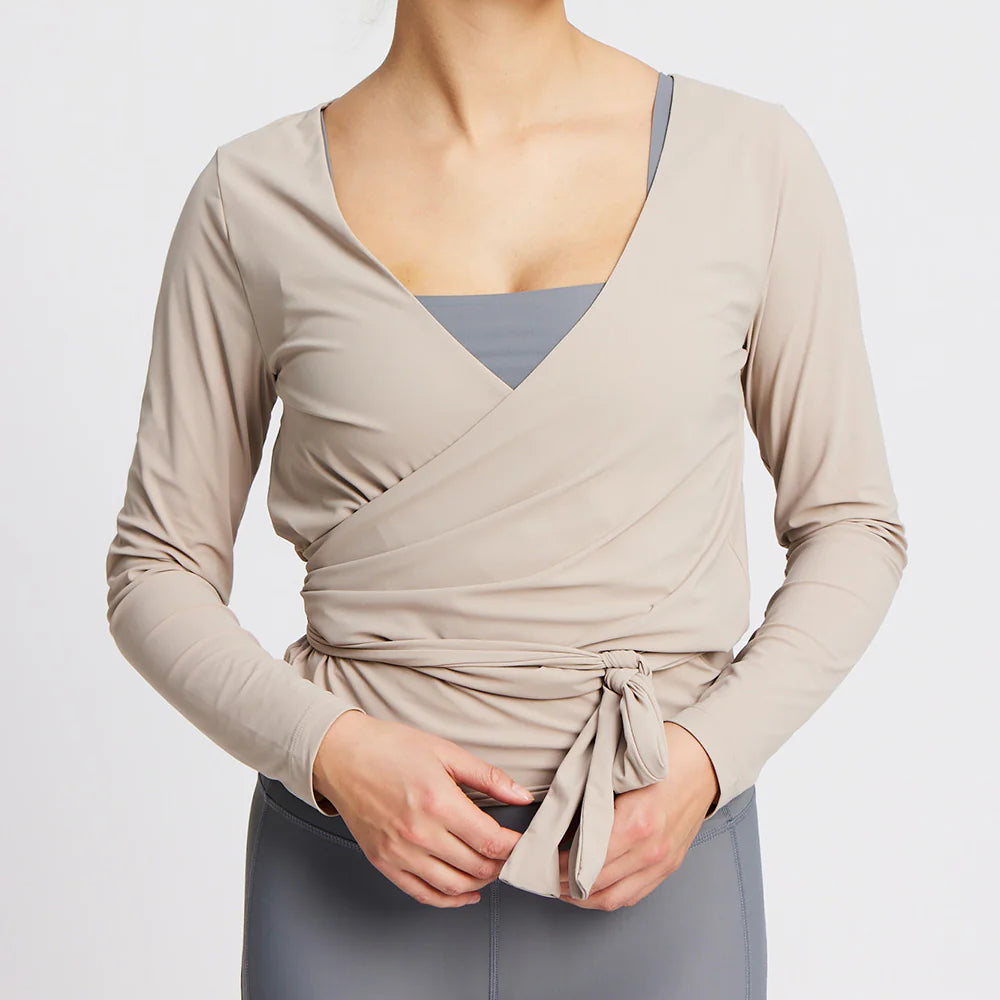 Person in beigem Wickeloberteil und grauer Leggings, im Halbprofil der obere Körperteil sichtbar.