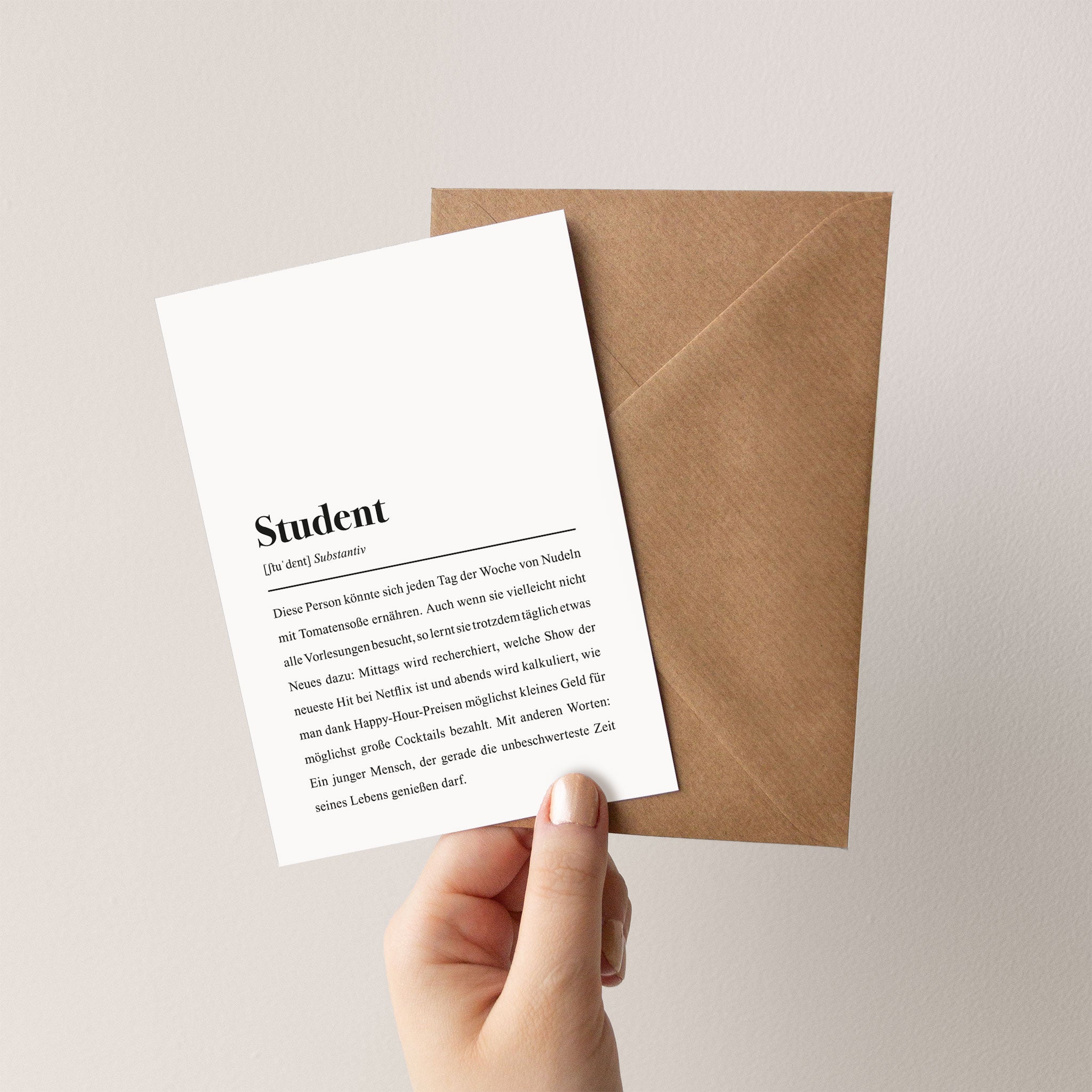 Eine Hand hält eine Grußkarte mit der Überschrift "Student" vor einem braunen Umschlag.