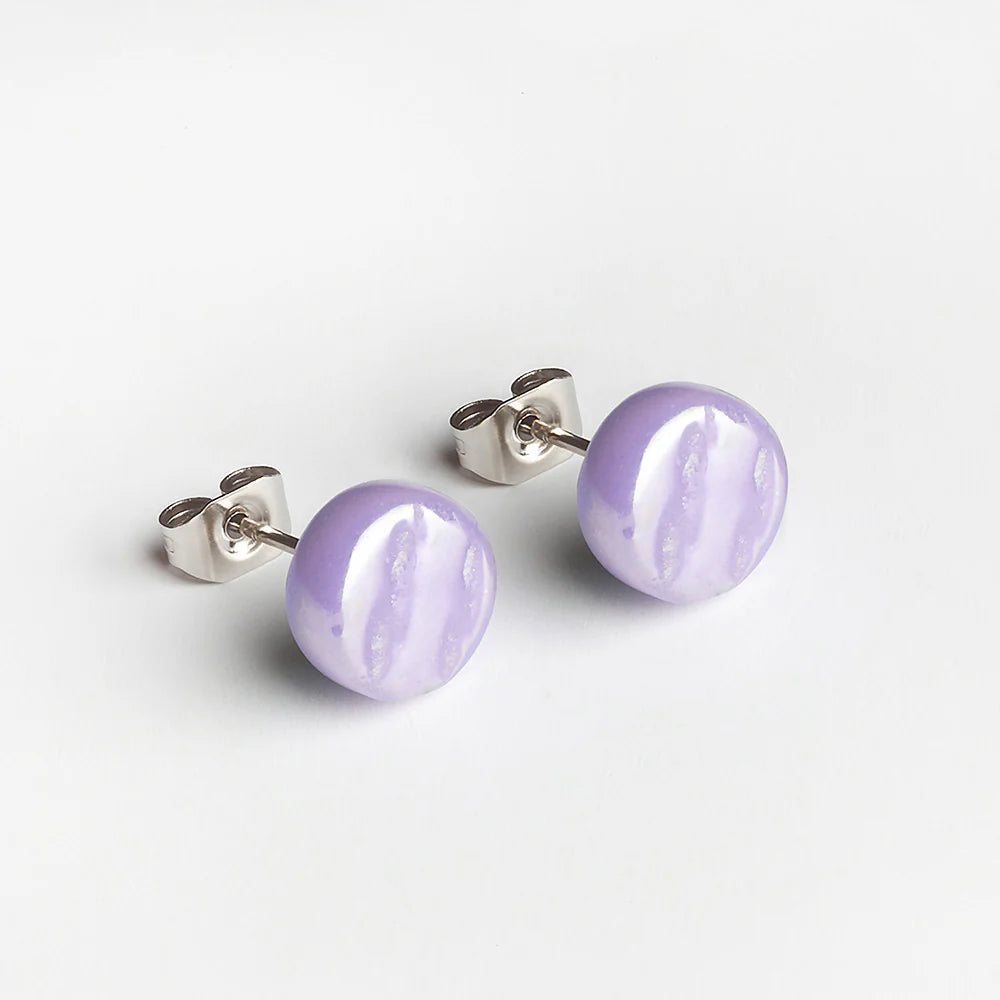 Ein Paar runde, hellviolette Ohrstecker mit glänzender Oberfläche und silbernen Stiften auf weißem Hintergrund.