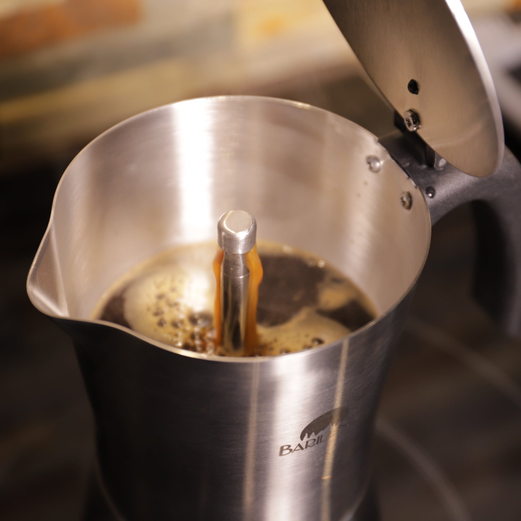 Moka-Kanne in Nahaufnahme, in der Kaffee gekocht wird, mit geöffnetem Deckel und dampfendem Kaffee.