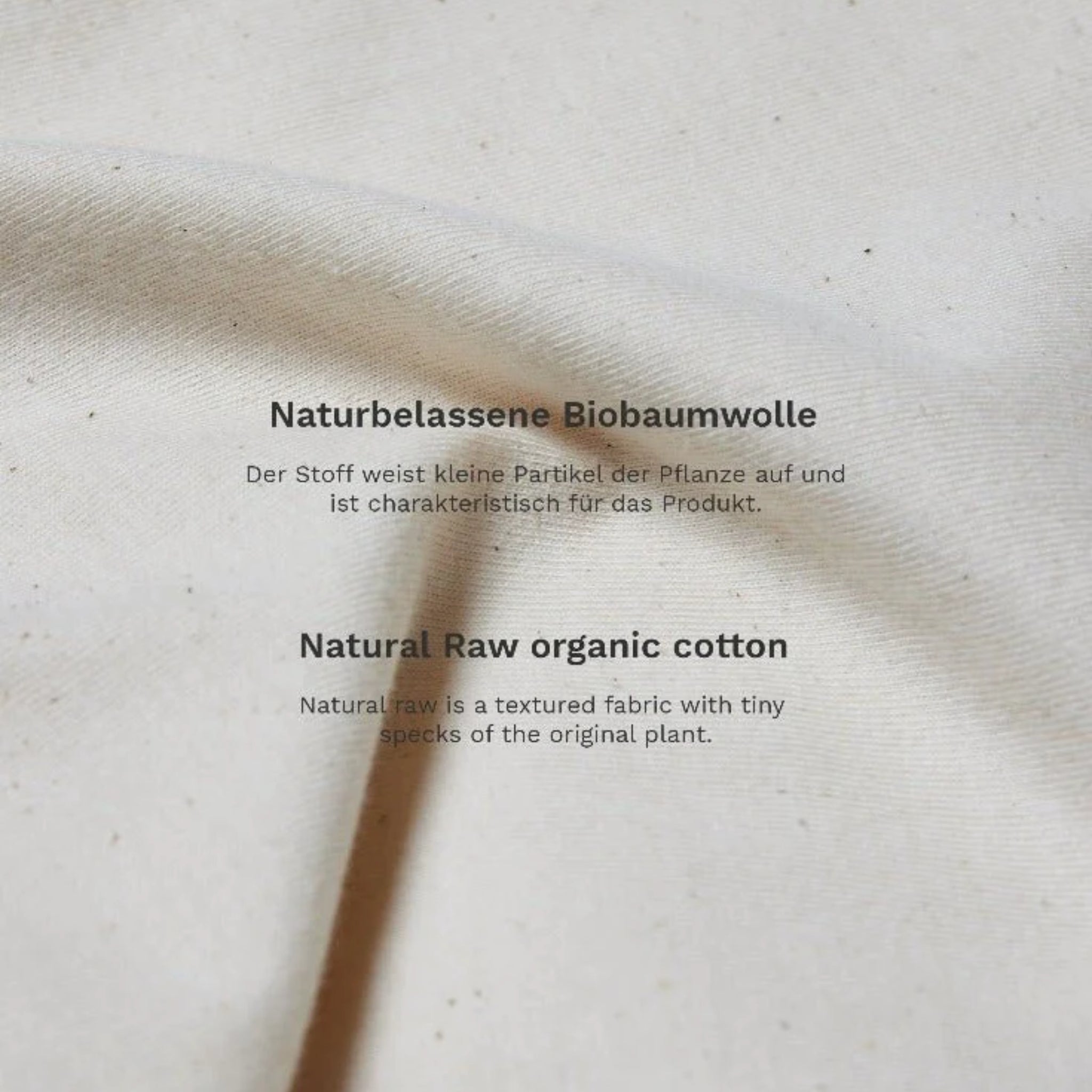 Weiße Biobaumwolle mit Text über natürliche Rohbaumwollstruktur, auf Deutsch und Englisch, sichtbar auf dem Stoff.