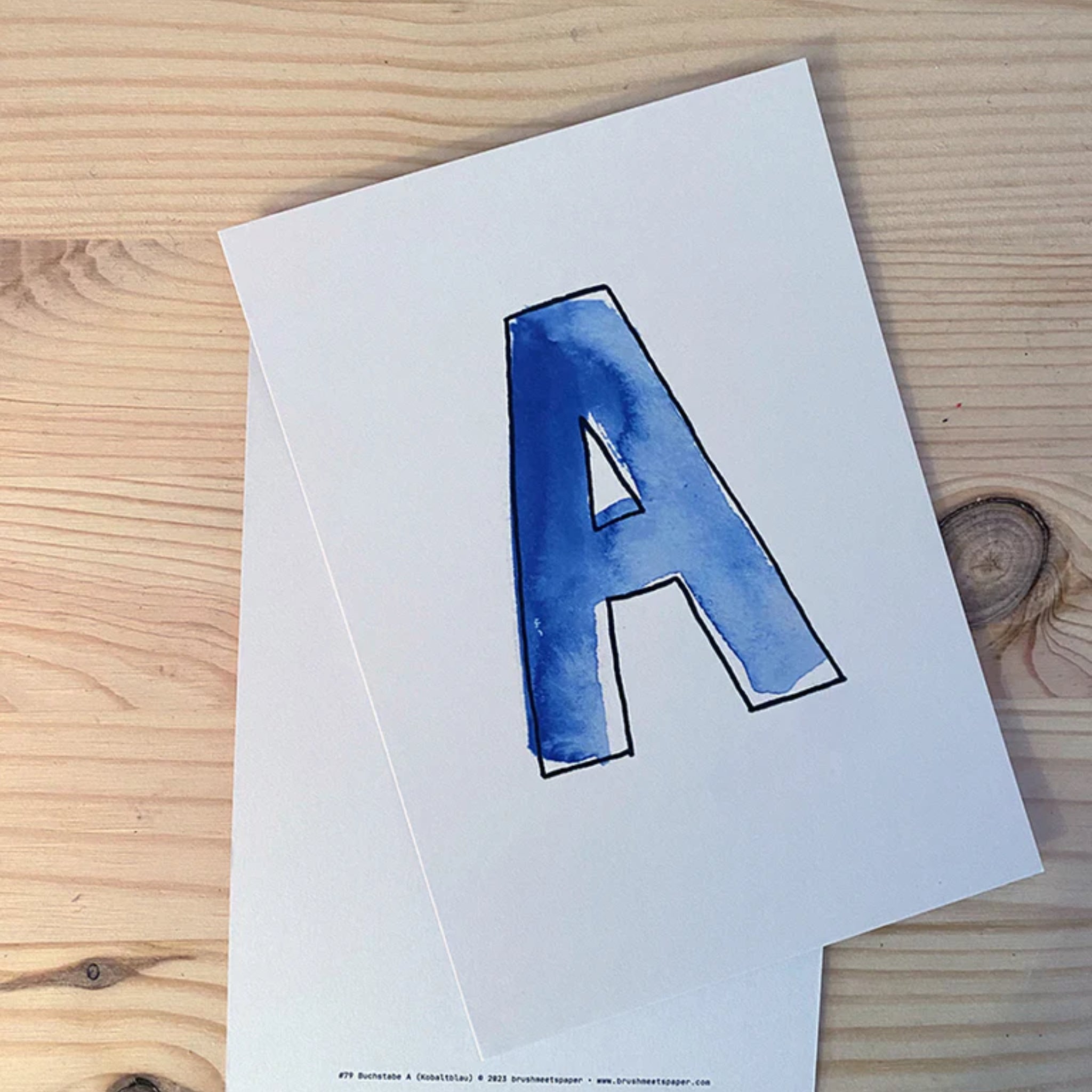 Eine Karte mit dem blauen Buchstaben "A" auf Holzuntergrund.