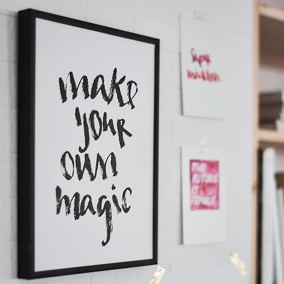 Schwarzer Rahmen mit dem Schriftzug "Make your own magic"; daneben sind weitere Zitate an der Wand.