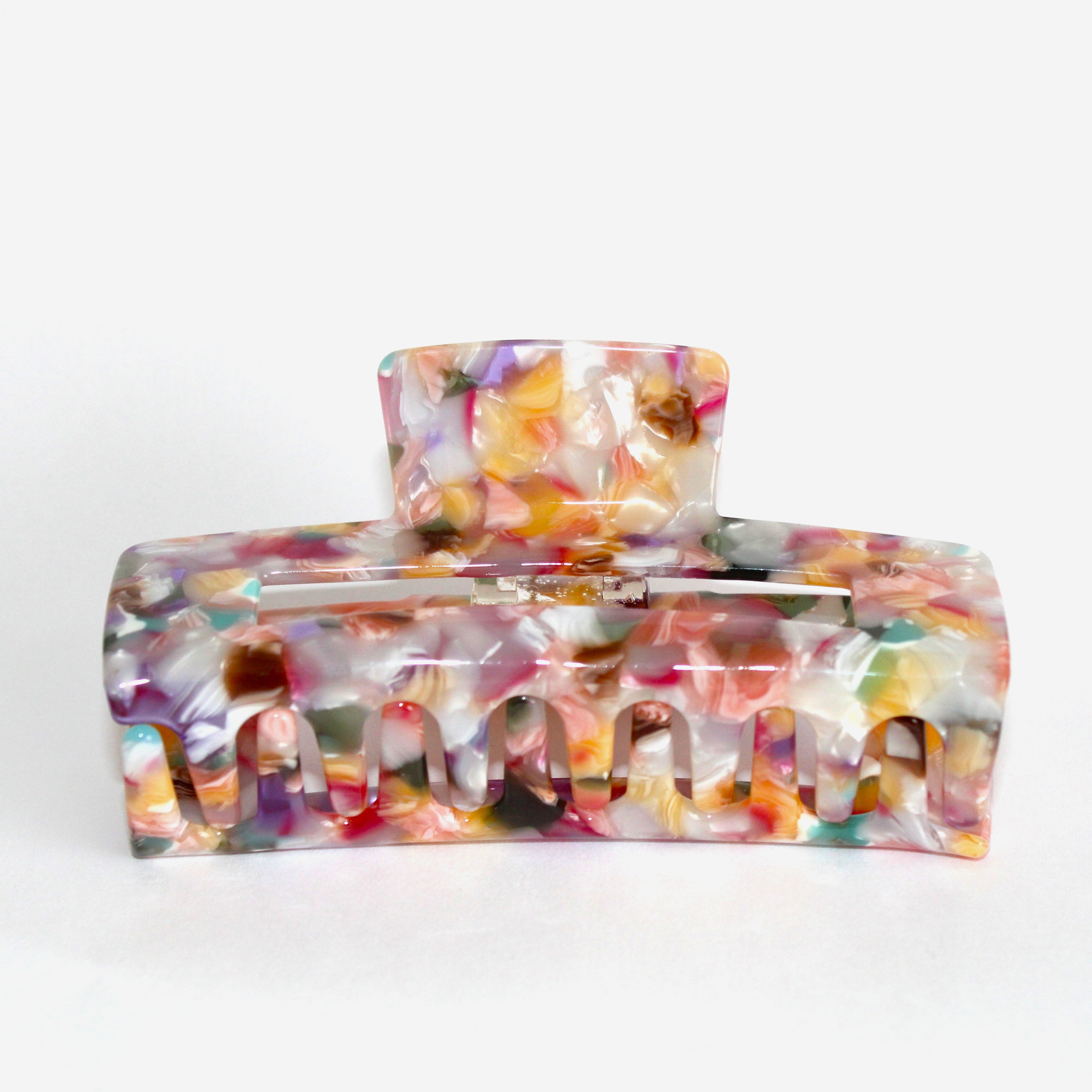 Bunte Haarspange mit marmoriertem Muster in Pastelltönen auf weißem Hintergrund.