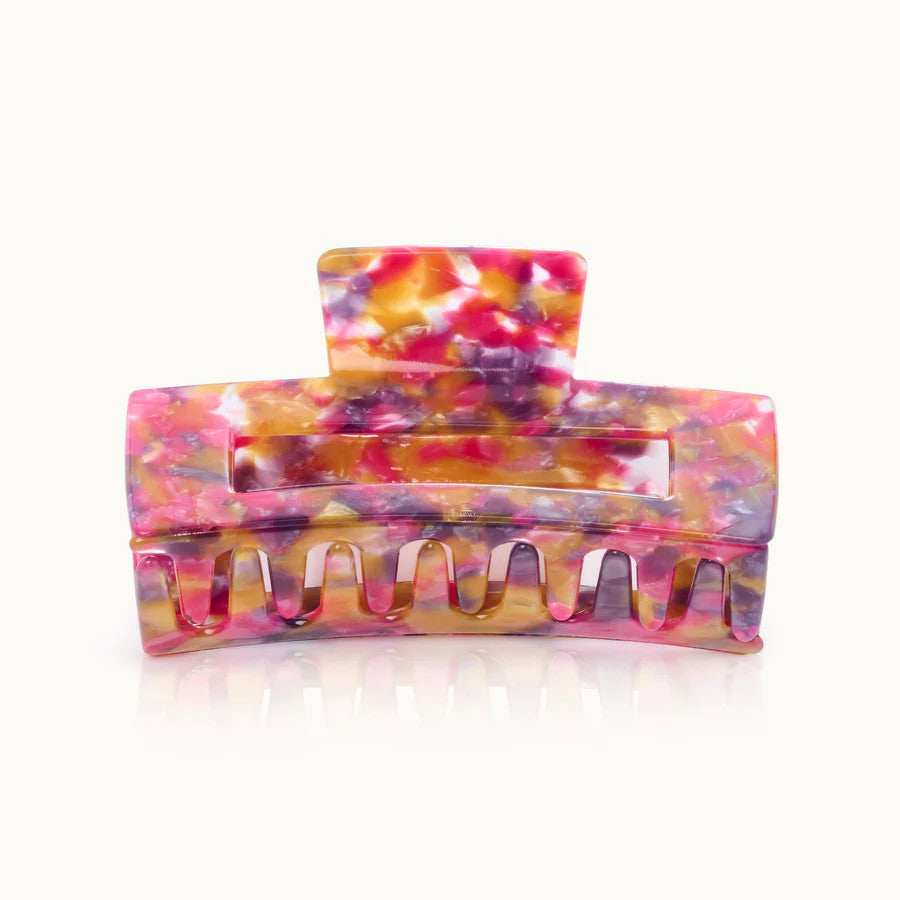 Bunte Haarspange in Marmoroptik mit rosa, gelben und lila Tönen auf hellgrauem Hintergrund.