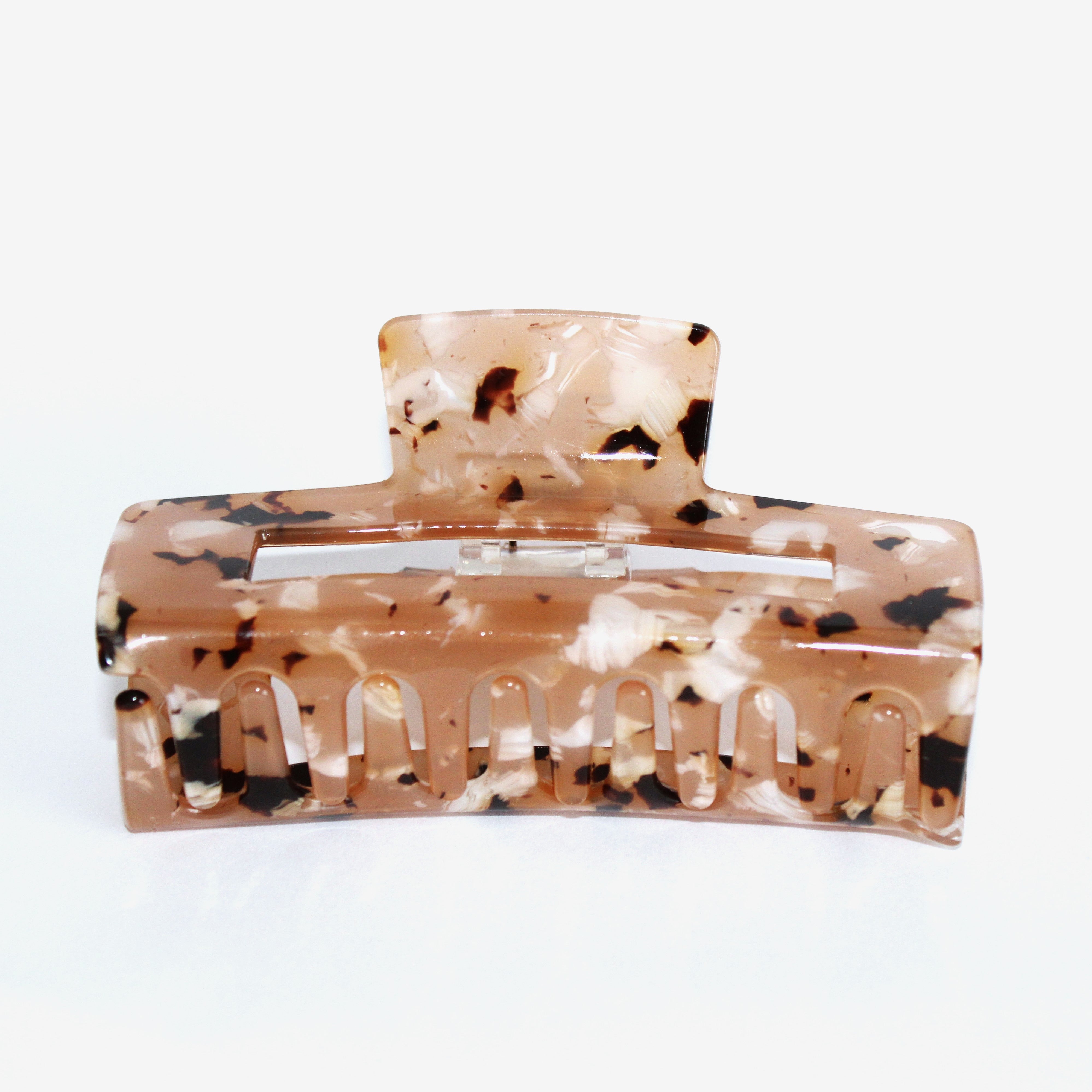 Haarklammer aus braunem Kunststoff mit schwarzem und weißem marmorierten Muster, auf weißem Hintergrund.