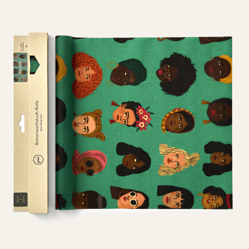 Grüne Bienenwachstuch-Rolle mit bunten, illustrierten Frauenköpfen in verschiedenen Frisuren und Stilen.