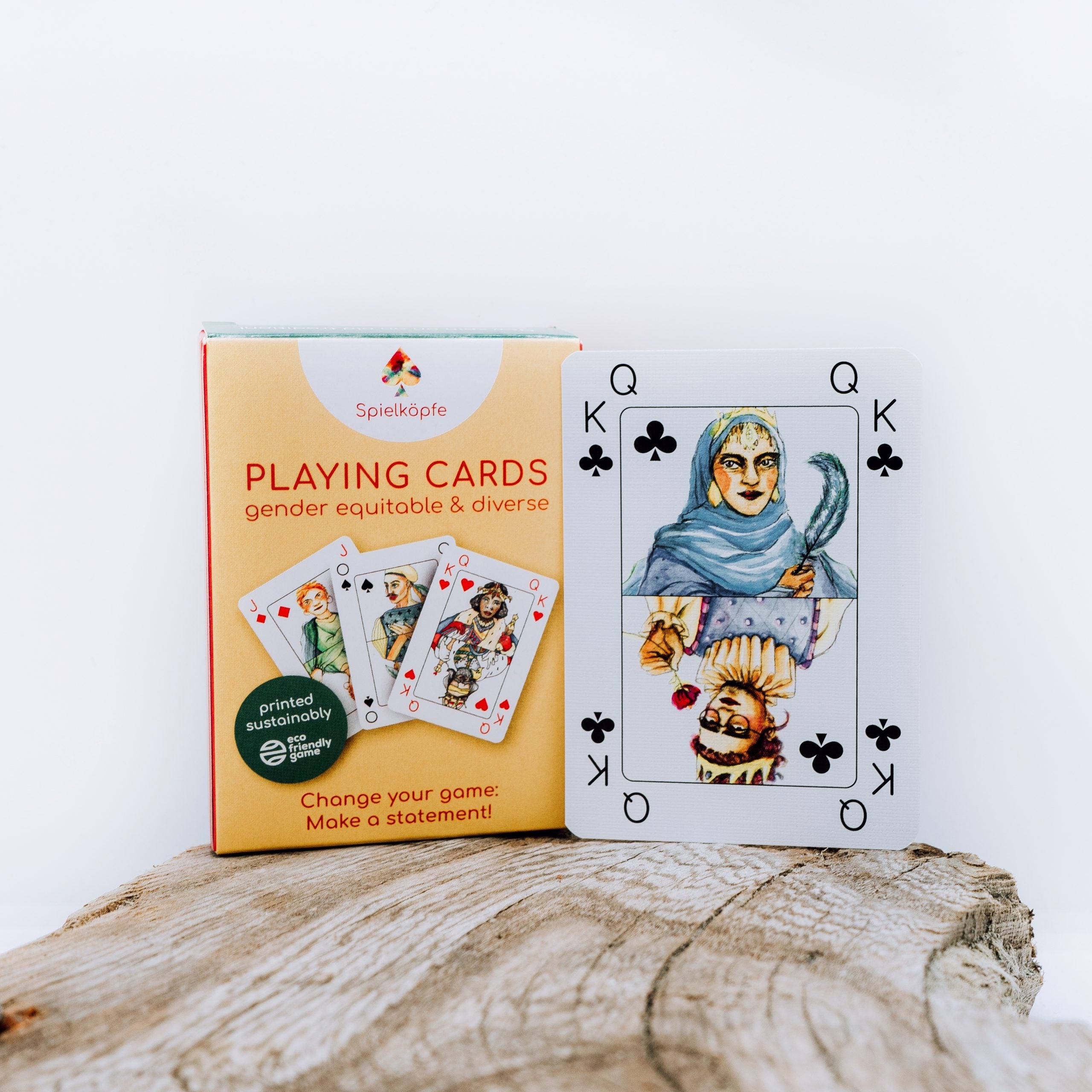 Spielkarte mit geschlechtsgerechter und vielfältiger Darstellung neben passender Verpackung auf Holztisch.