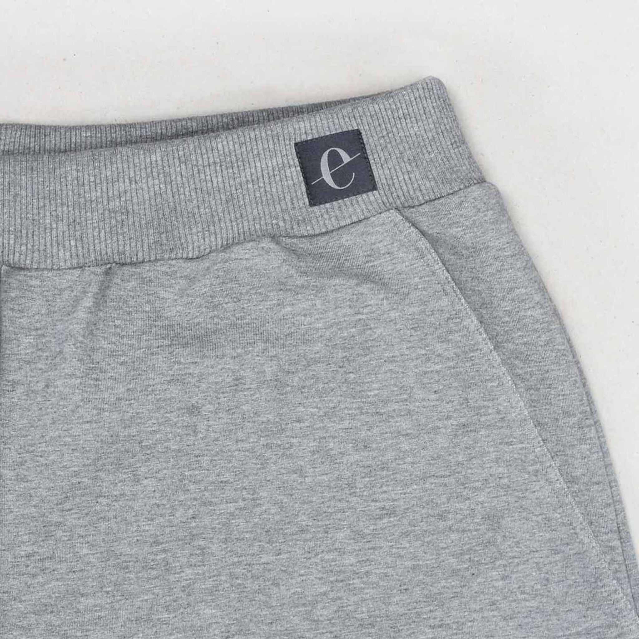 Graue Jogginghose mit einem schwarzen Etikett am Bund, auf dem ein kleines, weißes "e" steht.