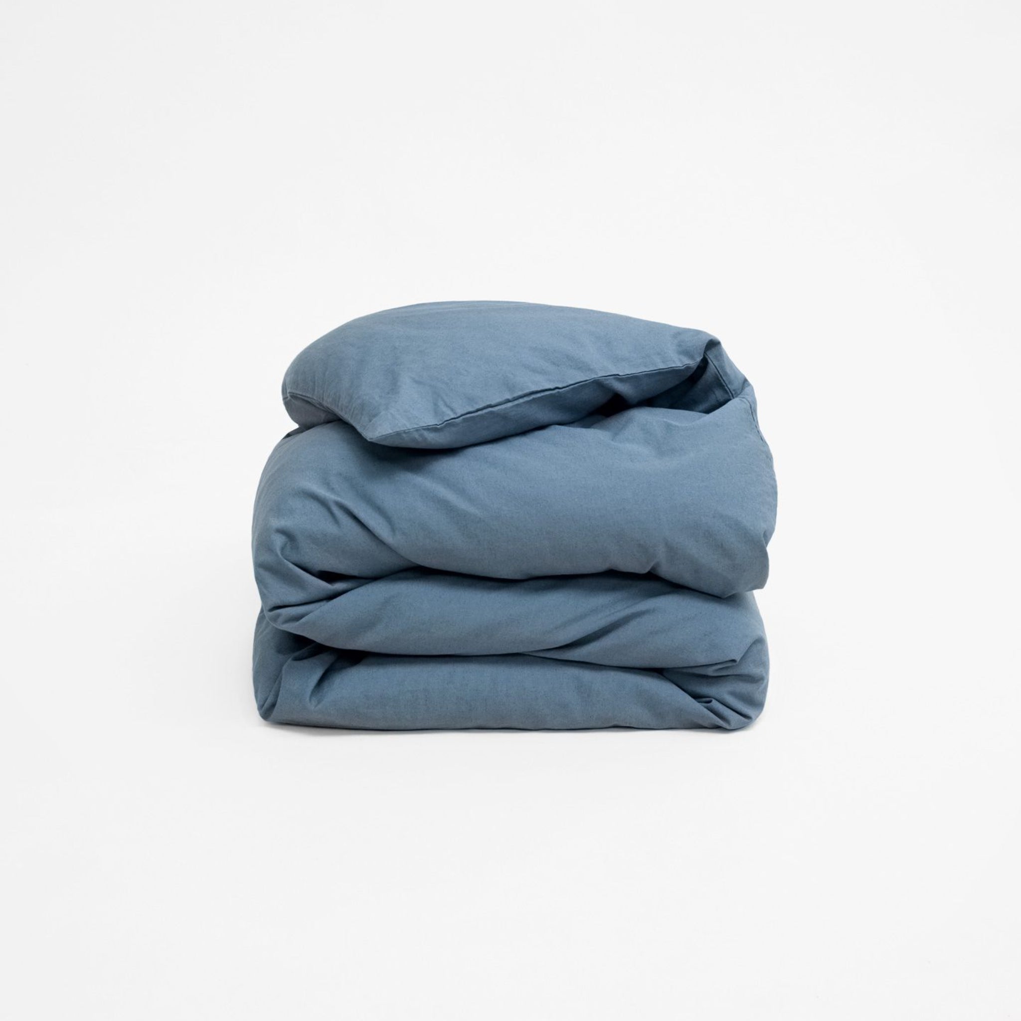 Zusammengefaltete blaue Decke auf neutralem Hintergrund.