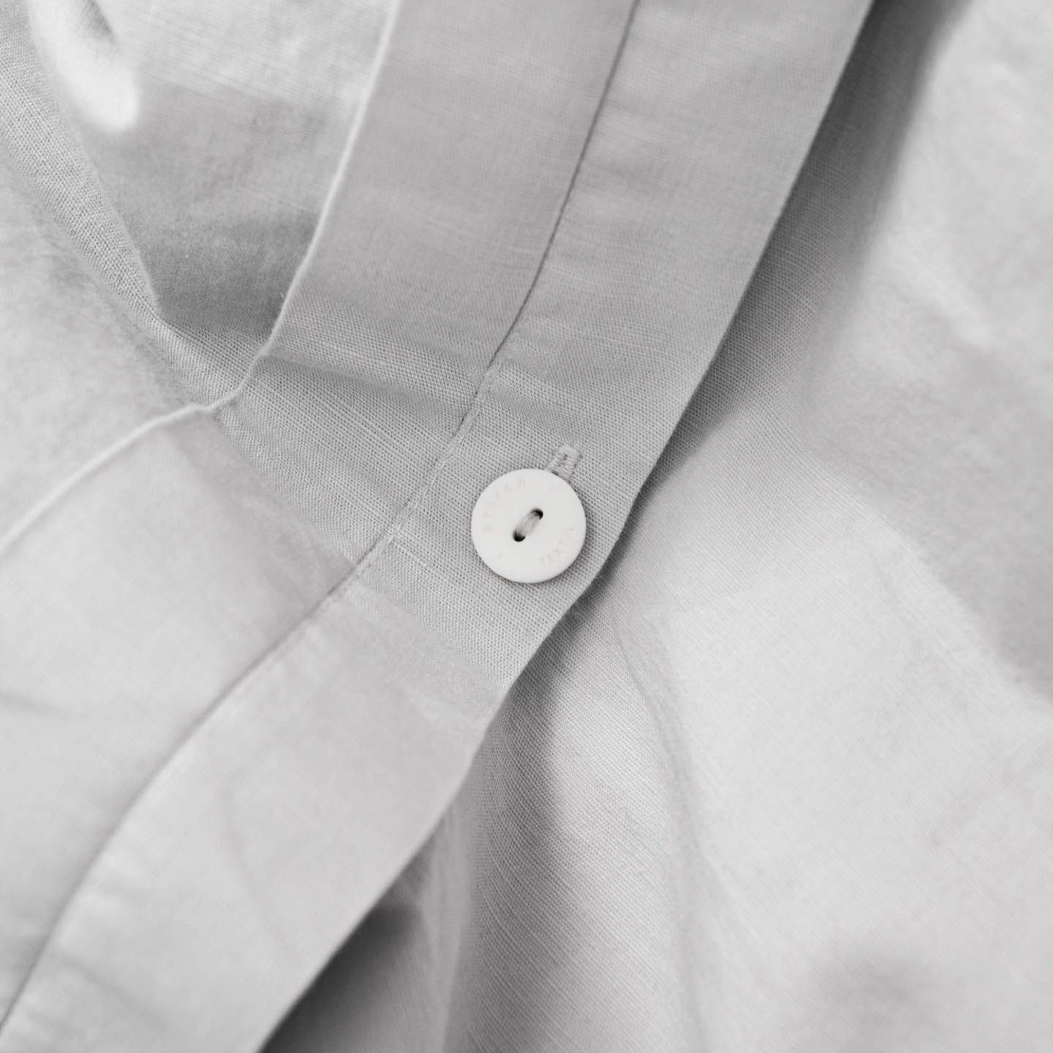 Nahaufnahme eines weißen Hemdes mit einem Knopf.