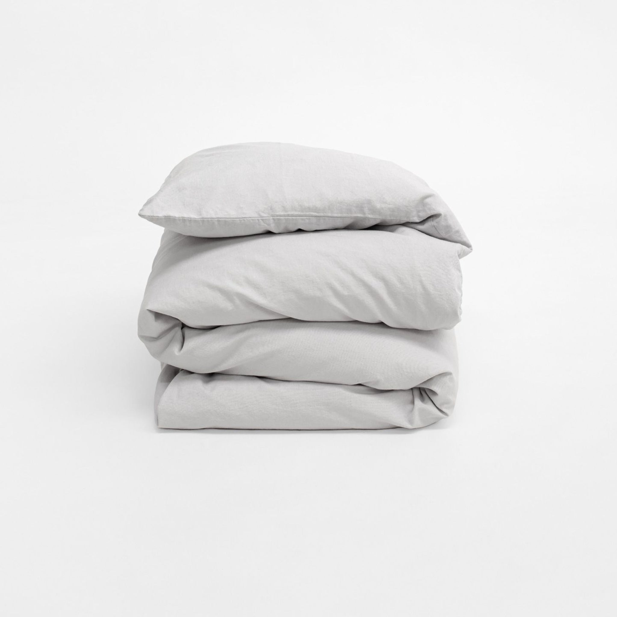 Grau geknüllte Bettwäsche, sauber gefaltet, auf einem weißen Hintergrund.