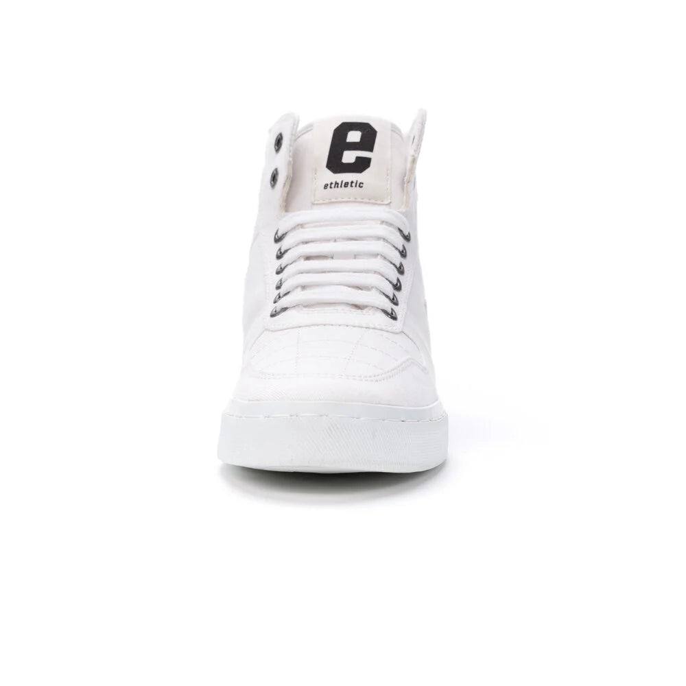 Ein weißer High-Top-Sneaker, von vorne gesehen, mit schwarzen Schnürsenkelösen und einem großen schwarzen Buchstaben e auf der Zunge mit der Aufschrift e thetic auf weißem Hintergrund.