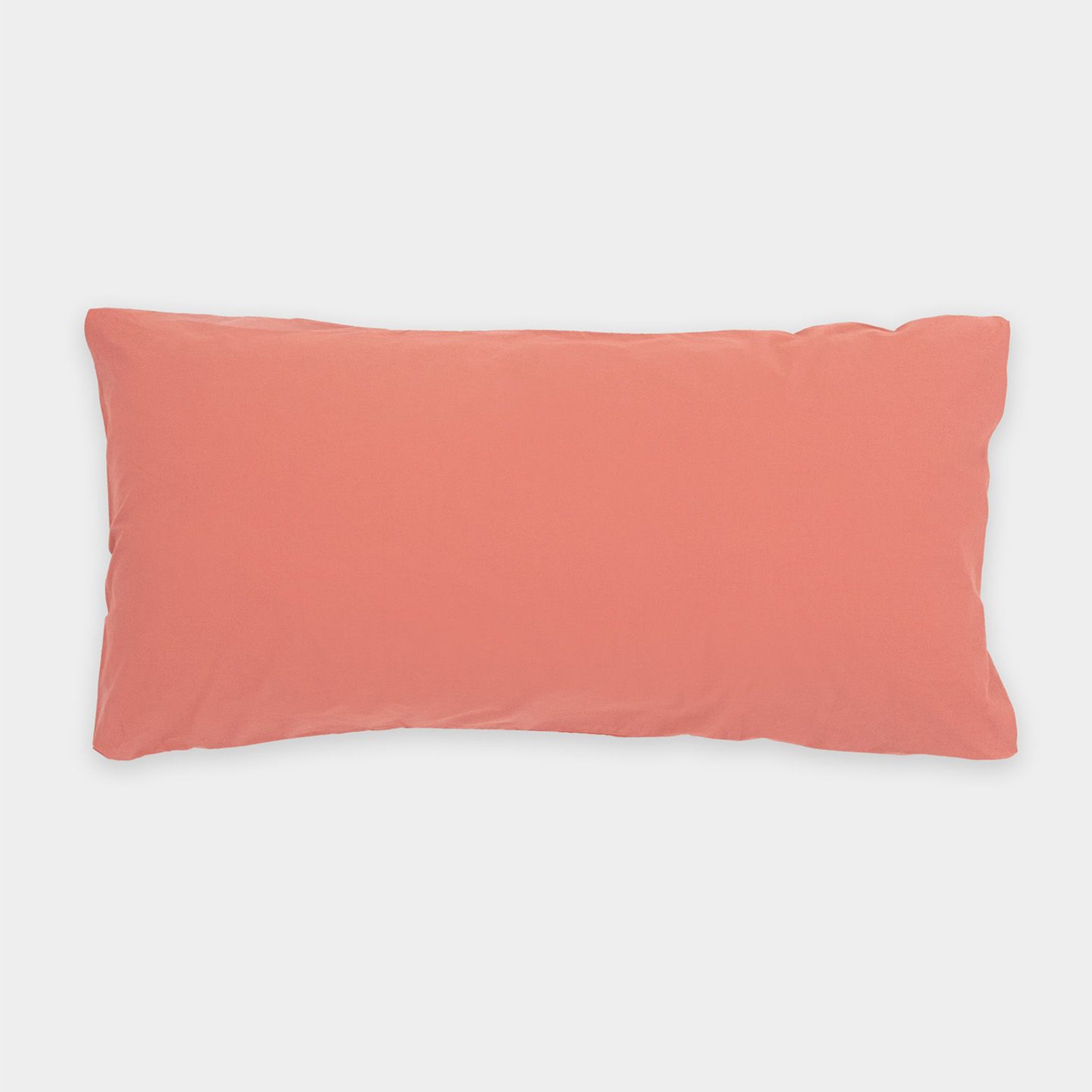 Ein rechteckiges, korallenfarbenes Kissen auf weißem Hintergrund.