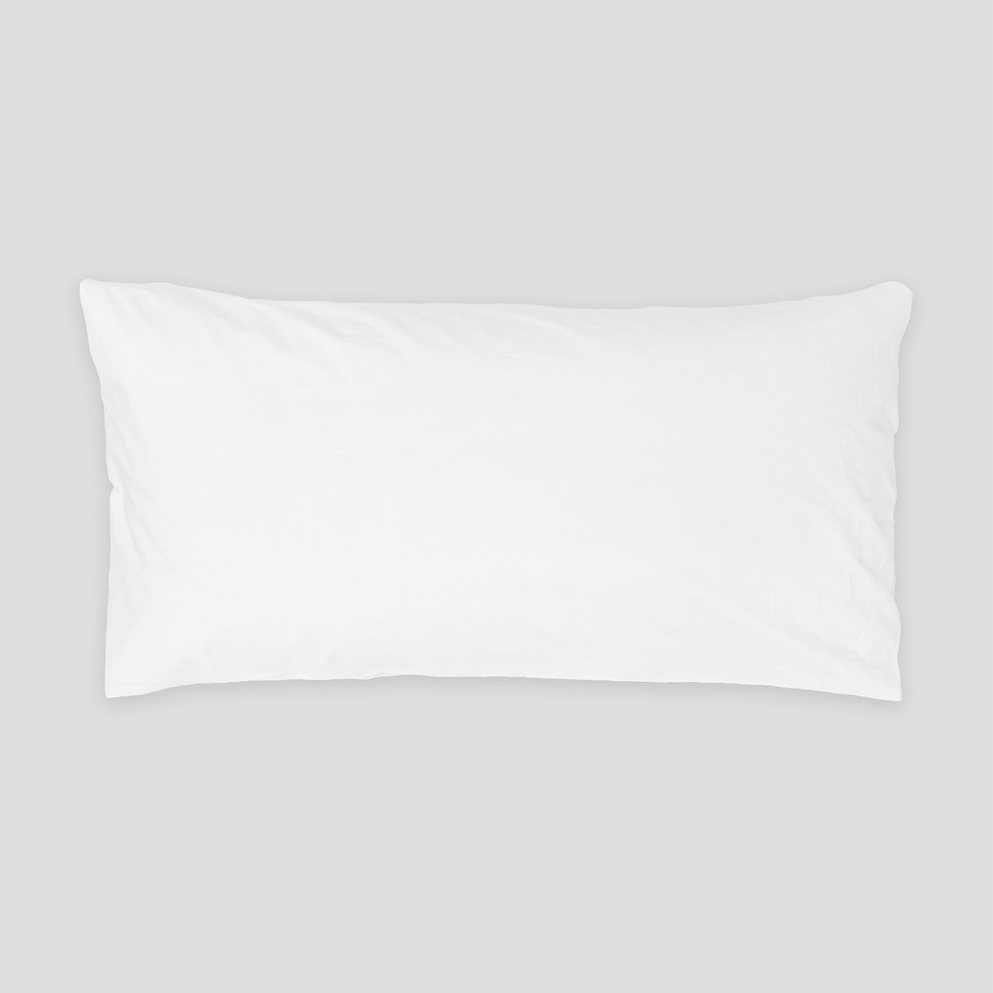 Ein rechteckiges, weißes Kissen liegt auf einem hellgrauen Hintergrund.