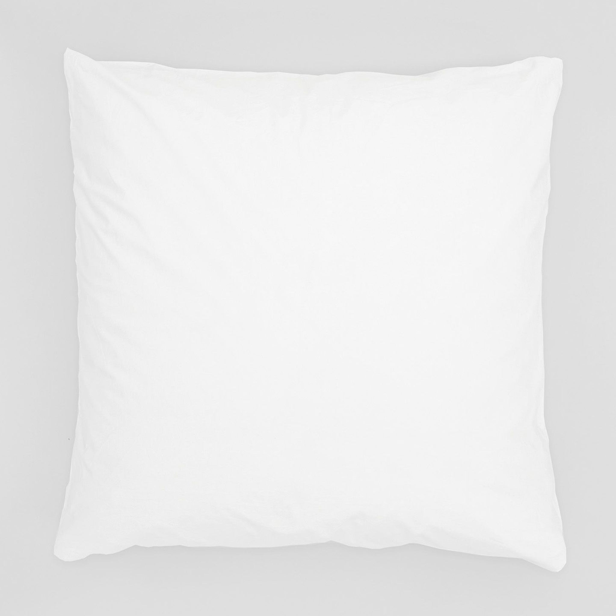 Ein weißes, quadratisches Kissen vor einem hellgrauen Hintergrund.