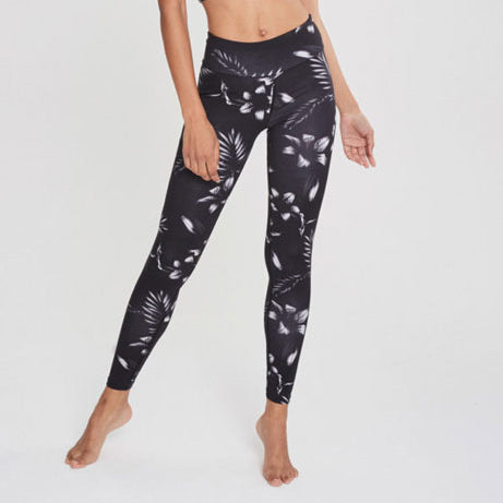 Person in schwarz-weißer Leggings mit floralem Muster auf weißem Hintergrund.