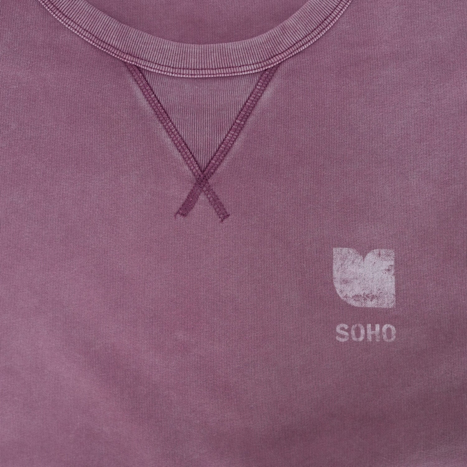 Lila T-Shirt mit sichtbarem Kragen und einem kleinen weißen "SOHO"-Logo unten rechts.