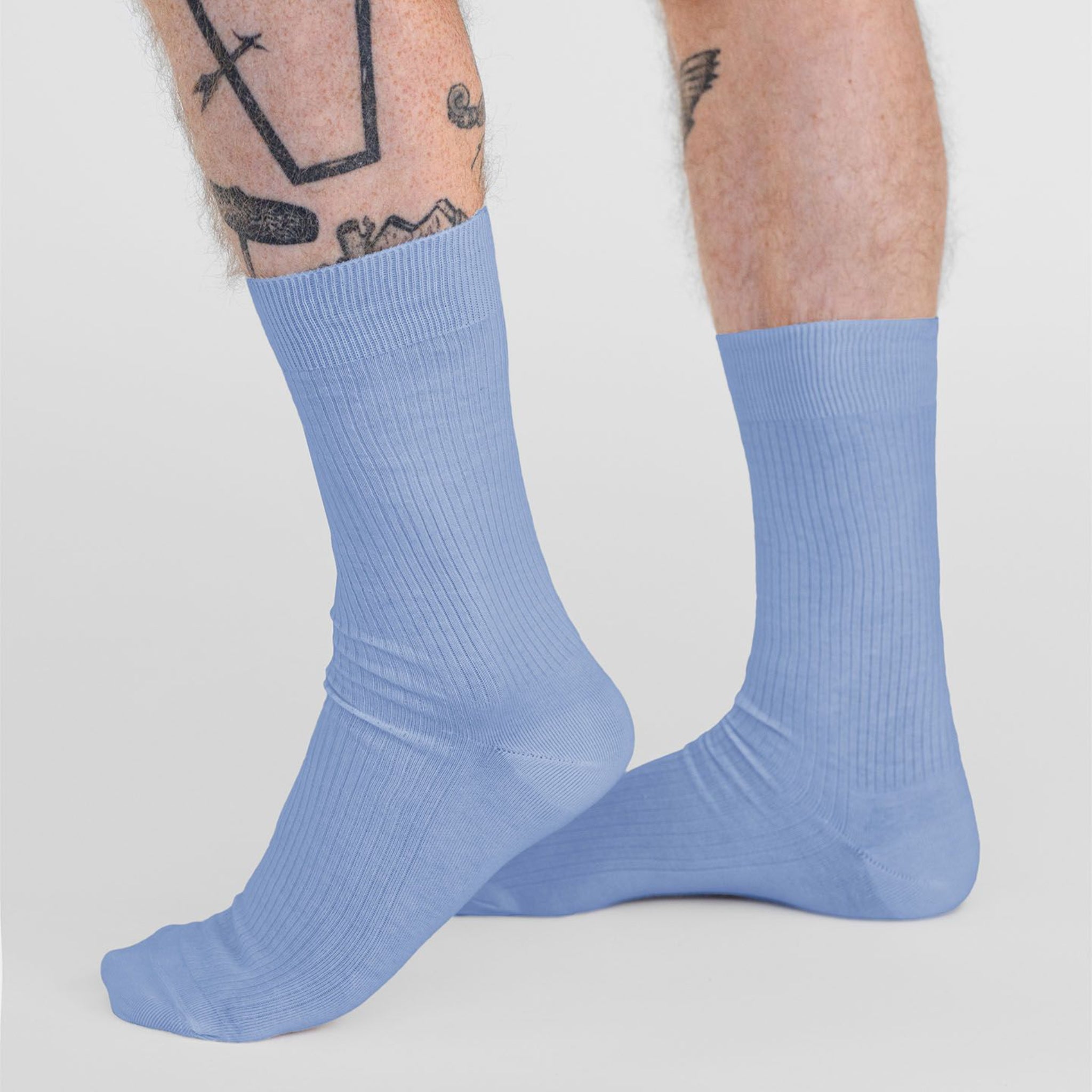 Beine mit Tattoos tragen hellblaue, gerippte Socken.