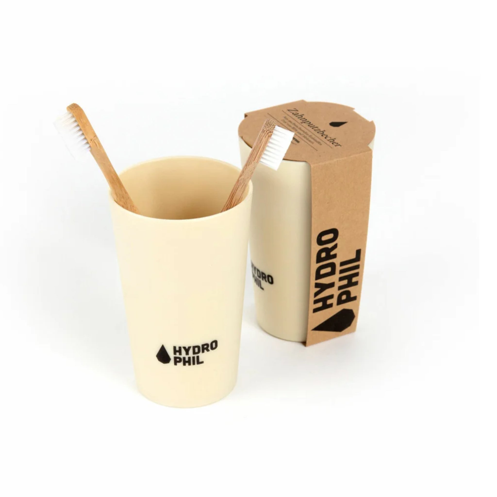 Zwei Bambuszahnbürsten in einem cremefarbigen Becher mit der Aufschrift "Hydrophil", daneben eine Verpackung.