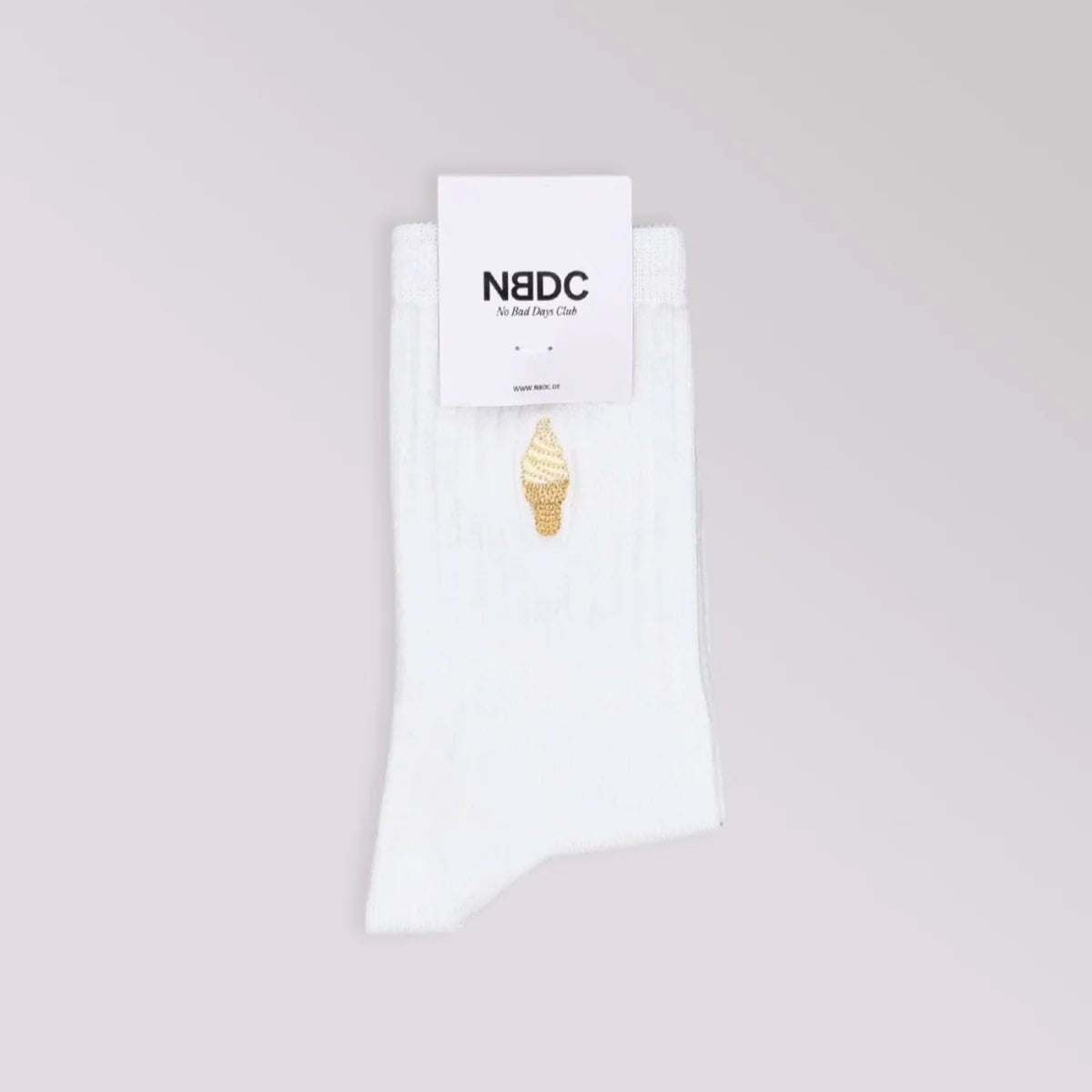Ein Paar weißer Socken mit einem kleinen gestickten Eistütenmotiv, ordentlich gefaltet unter einem weißen NBDC-Markenetikett, das vor einem hellgrauen Hintergrund dargestellt ist.