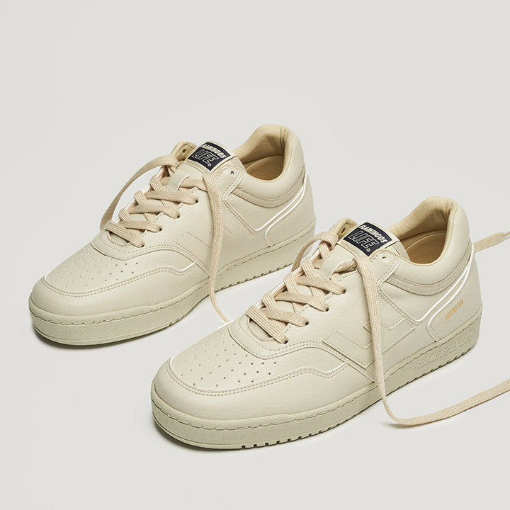 Cremefarbene Sneakers mit Schnürsenkeln auf hellem Hintergrund.