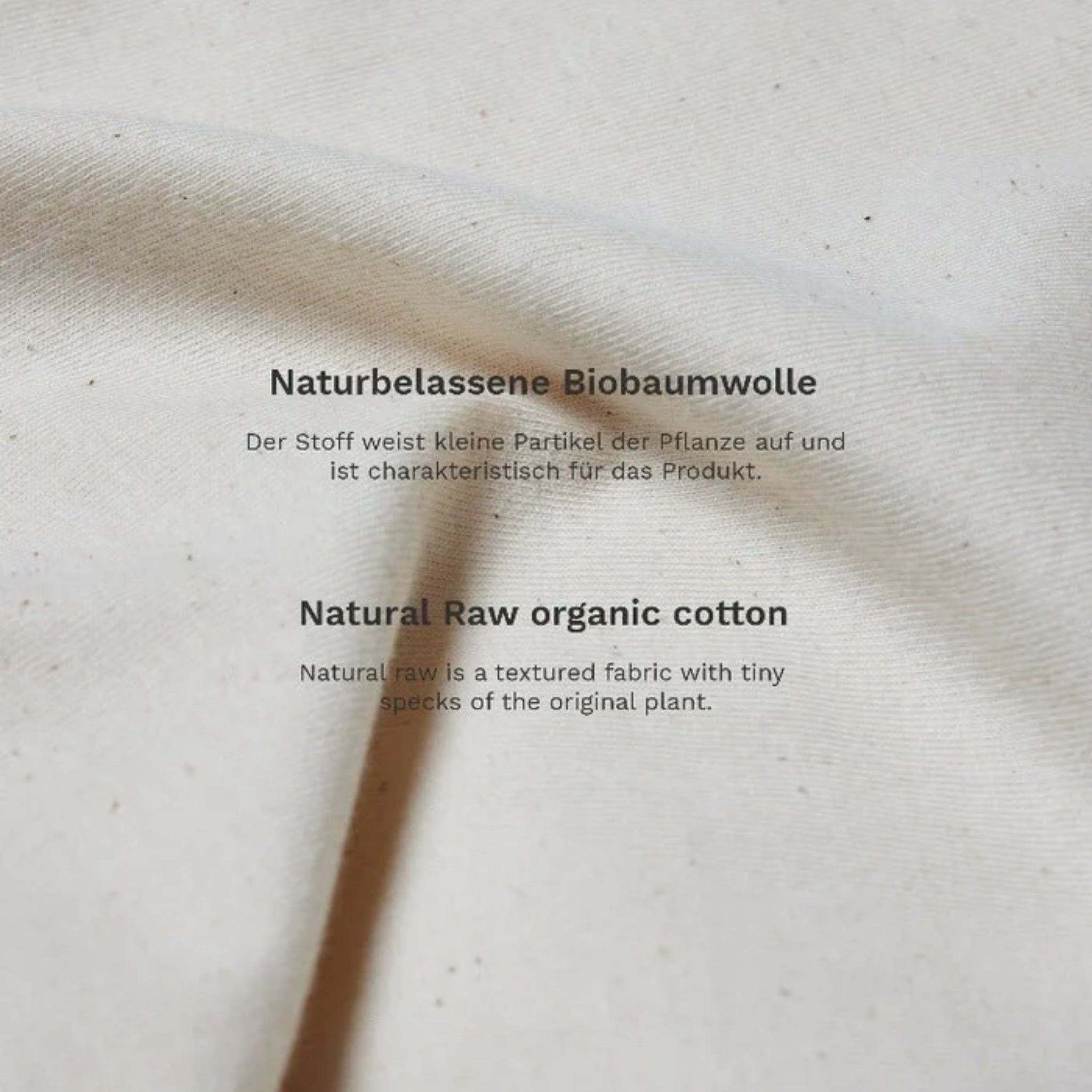 Nahaufnahme von naturbelassener Biobaumwolle mit Text über die Eigenschaften des Stoffes in Deutsch und Englisch.