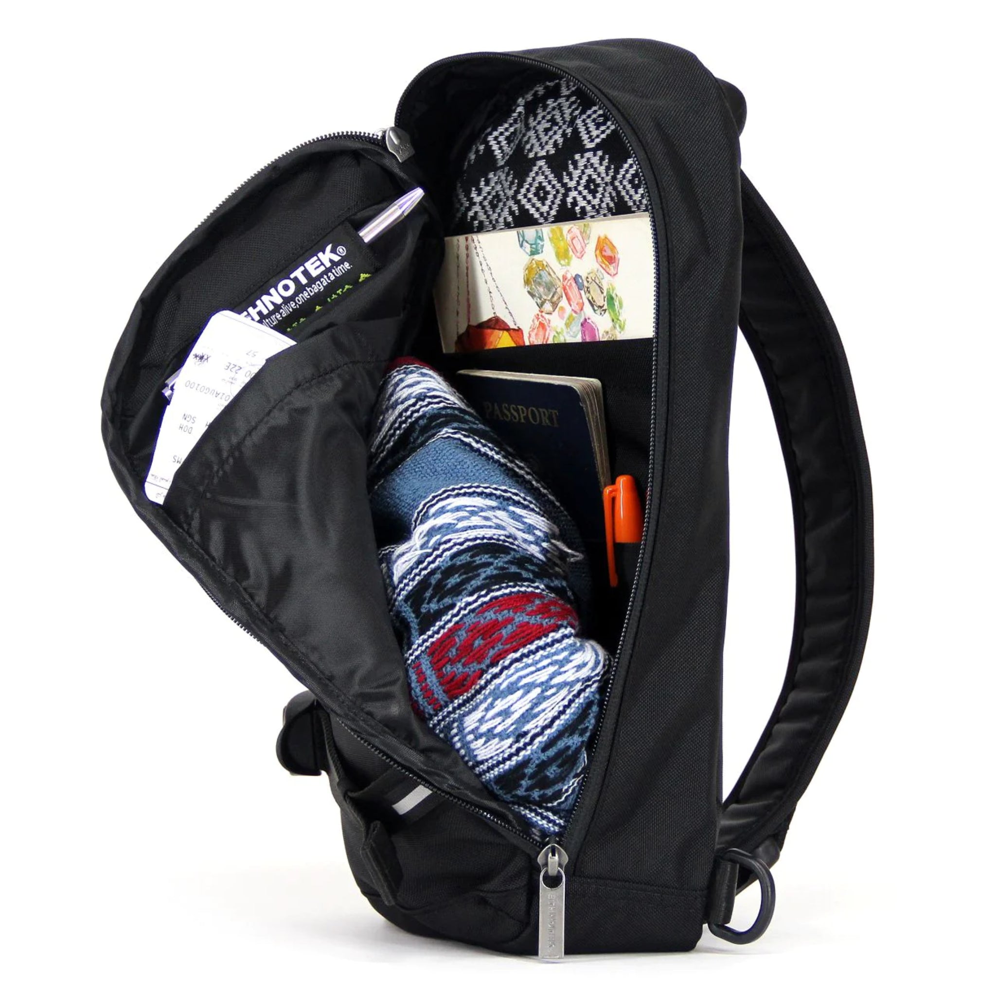 Ein geöffneter schwarzer Rucksack zeigt Inhalte wie einen Reisepass, ein gemustertes Tuch, einen Stift und Dokumente.