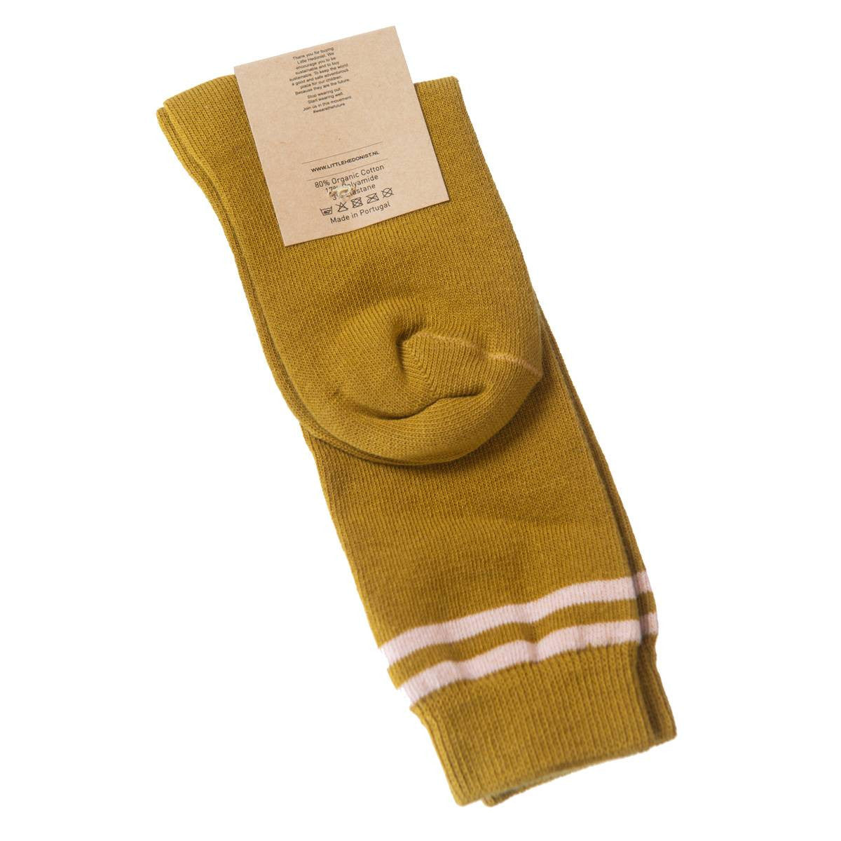 Ein Paar senfgelbe Socken mit zwei weißen Streifen am oberen Ende, ordentlich gefaltet und mit einem braunen Papieretikett versehen.