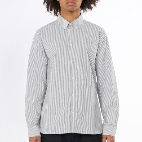 Person trägt ein gestreiftes Hemd mit langen Ärmeln vor weißem Hintergrund.