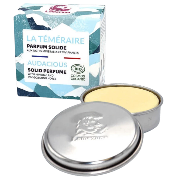 Feste Parfumdose von Lamazuna mit geöffneter Metallverpackung und Schachtel mit blau-weißem Design im Hintergrund.