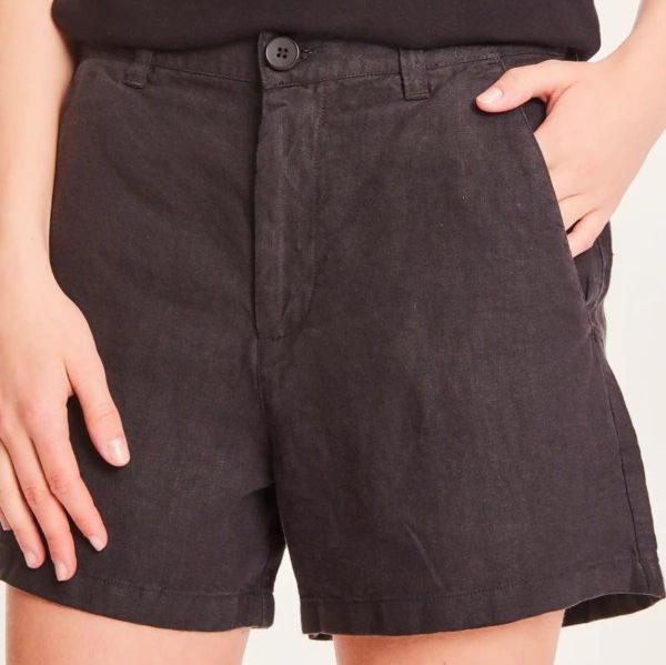 Person trägt eine schwarze kurze Hose, eine Hand in der Tasche.