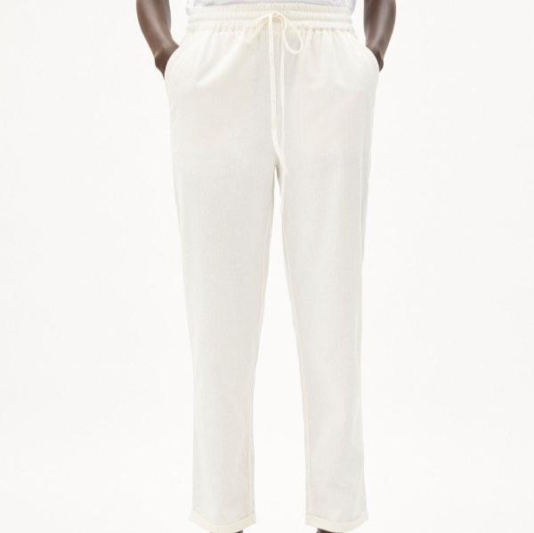 Person in weißer Hose mit Kordelzug und Taschen, vor neutralem Hintergrund.