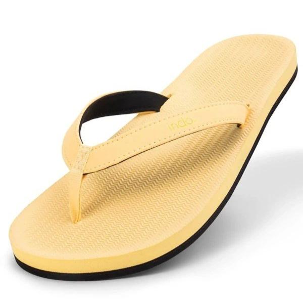 Gelber Flip-Flop mit schwarzer Sohle, schräg von oben fotografiert, auf weißem Hintergrund.