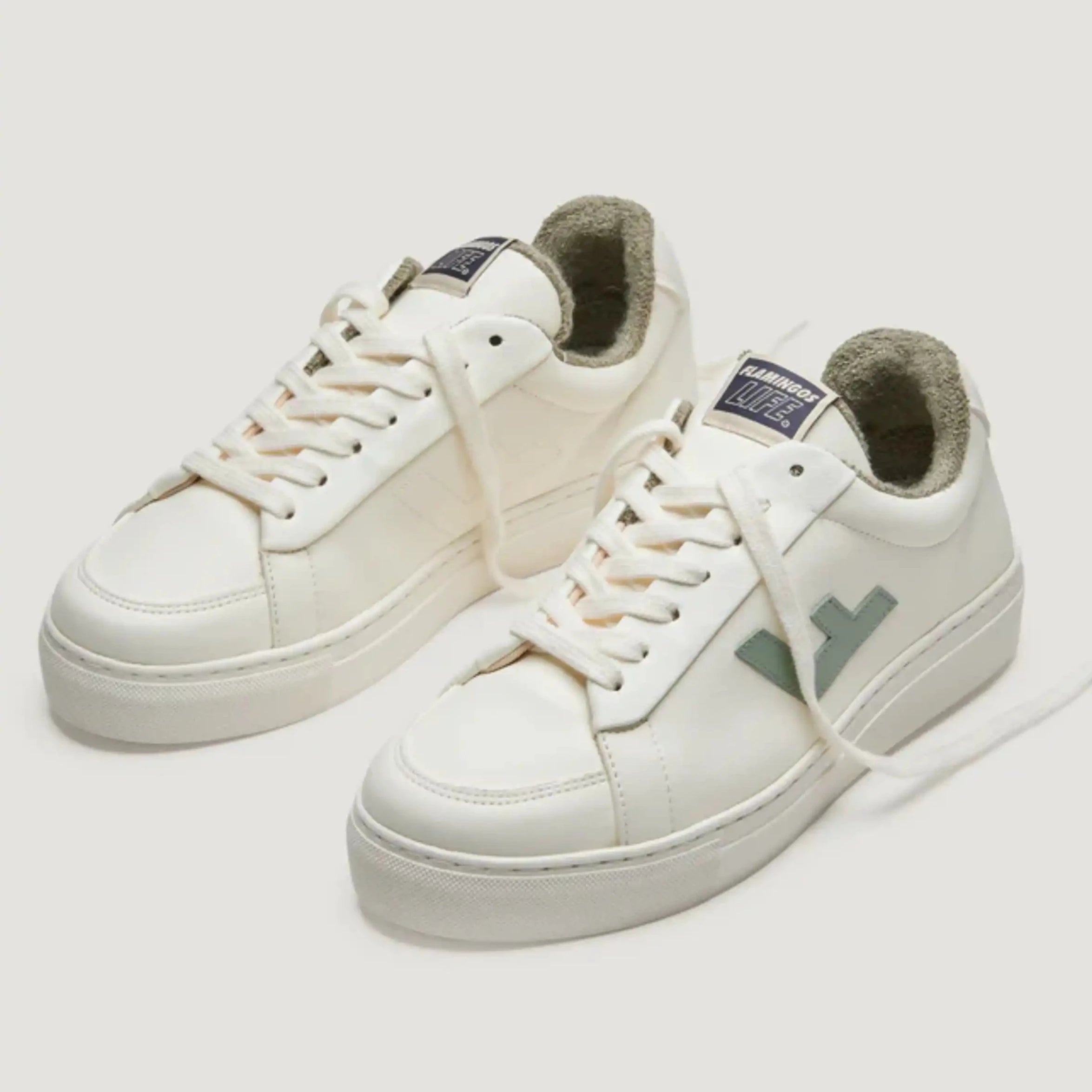 Weiße Sneakers mit Logo und weißer Sohle, vor weißem Hintergrund.