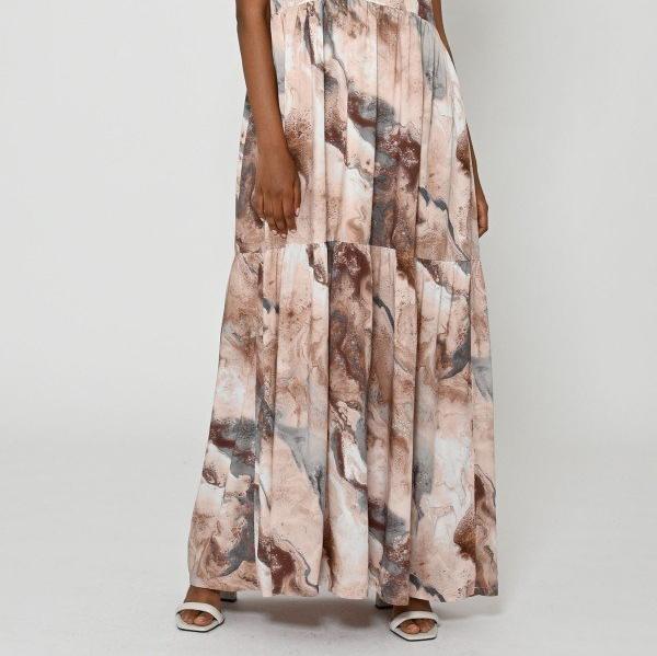 Person in a long, marble-patterned dress with shades of brown and gray, standing against a plain background.