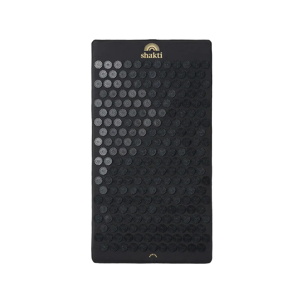 Eine schwarze Shakti-Akupressurmatte mit vielen kreisförmigen Stachelscheiben, die in einem Gittermuster angeordnet sind, und dem Shakti-Logo in Gold in der oberen Mitte.